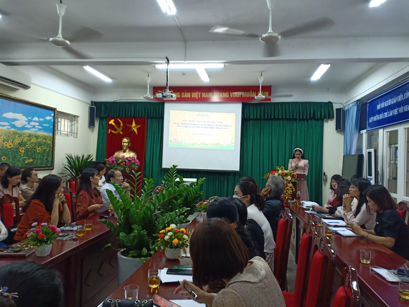 A group of people sitting in a room with a projector screenDescription automatically generated with low confidence