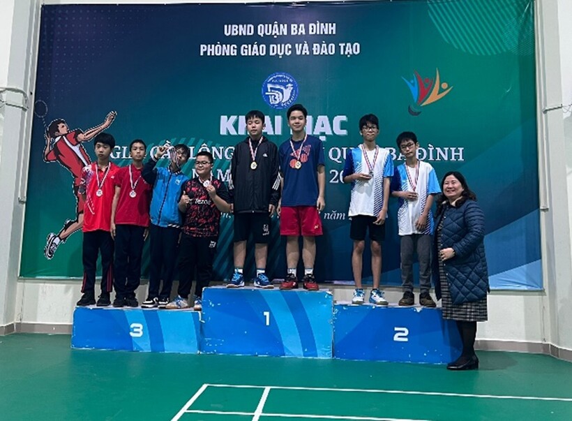 A group of people posing for a photo in front of a signDescription automatically generated with medium confidence