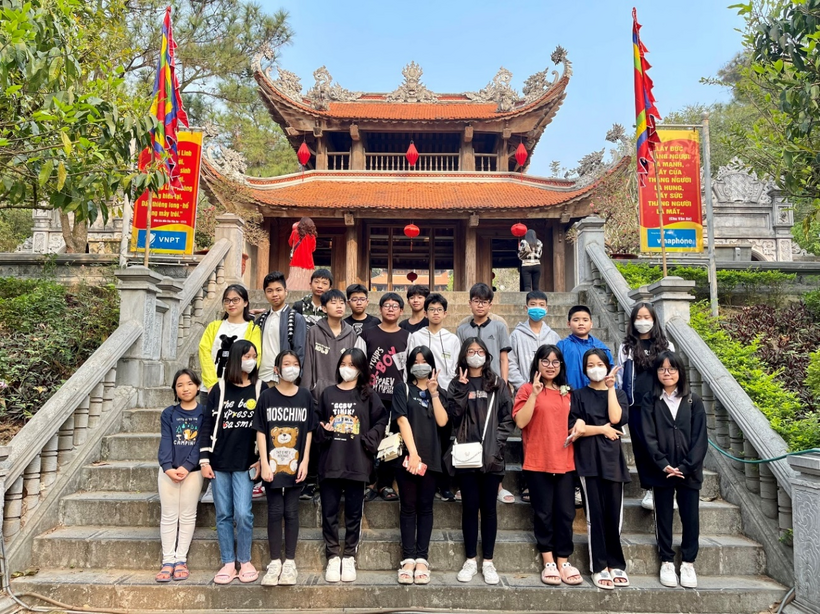 A group of people posing for a photo on stairs in front of a buildingDescription automatically generated with medium confidence