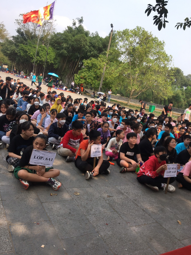 A large group of people sitting on the ground holding signsDescription automatically generated with medium confidence
