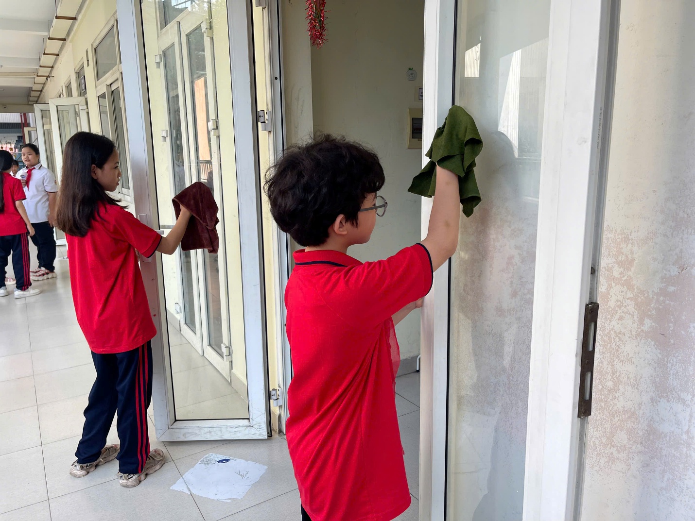 A child and child cleaning a glass doorAI-generated content may be incorrect.