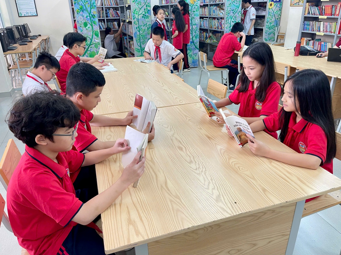 A group of children sitting at a table reading booksAI-generated content may be incorrect.