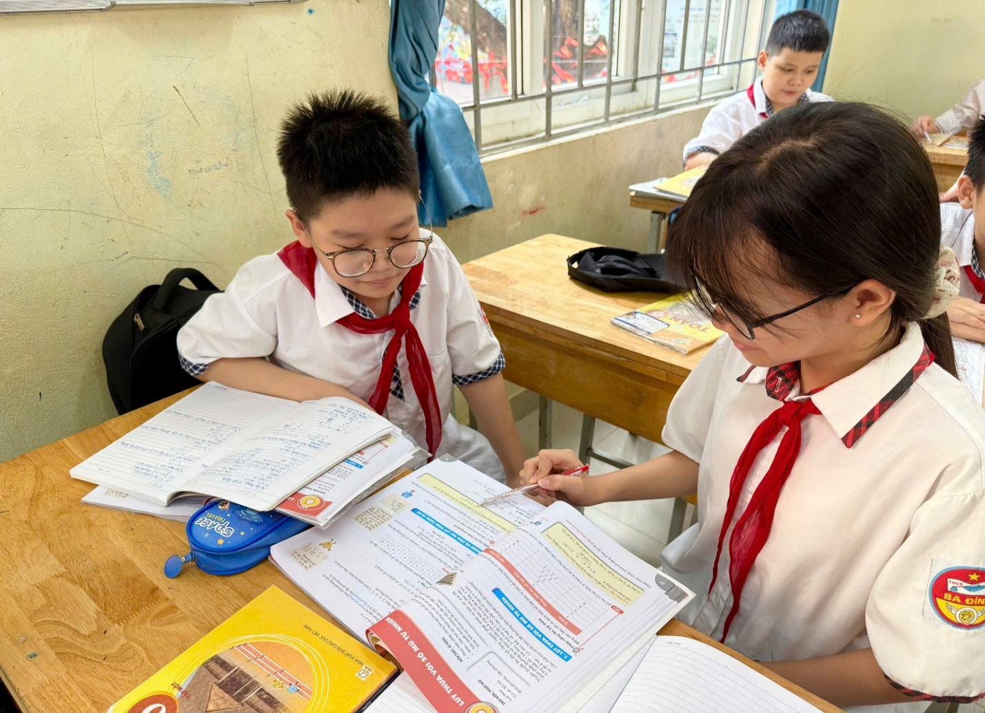 A person and child in uniform sitting at a desk with booksAI-generated content may be incorrect.