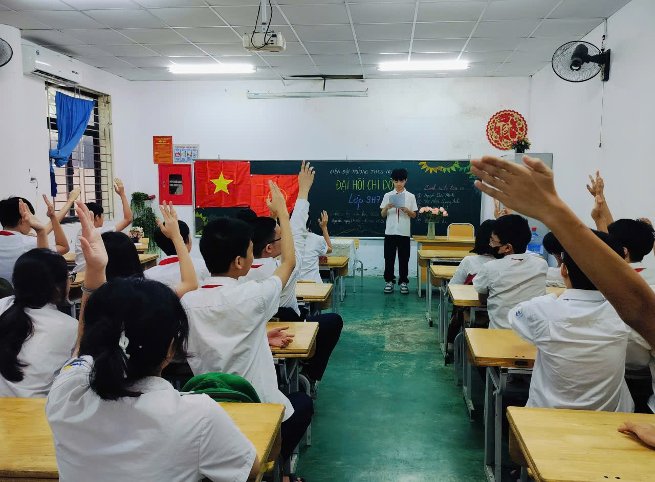 A group of people raising their hands in a classroom

Description automatically generated